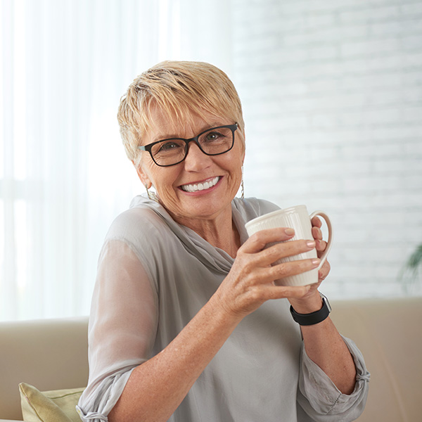 Happy woman smiling drinking a cup of tea in the afternoon
