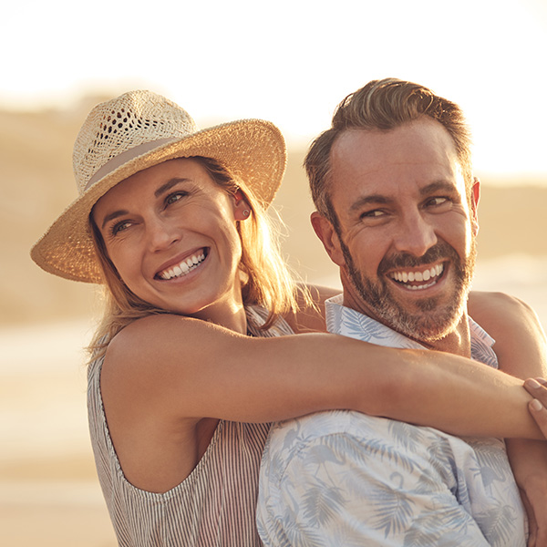 Happy couple smiling having a good time at the beach