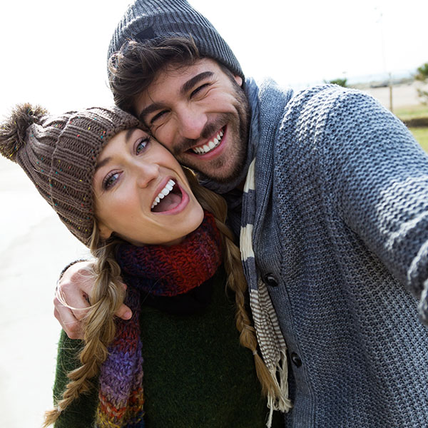 Happy couple smiling and wearing sweaters and hats
