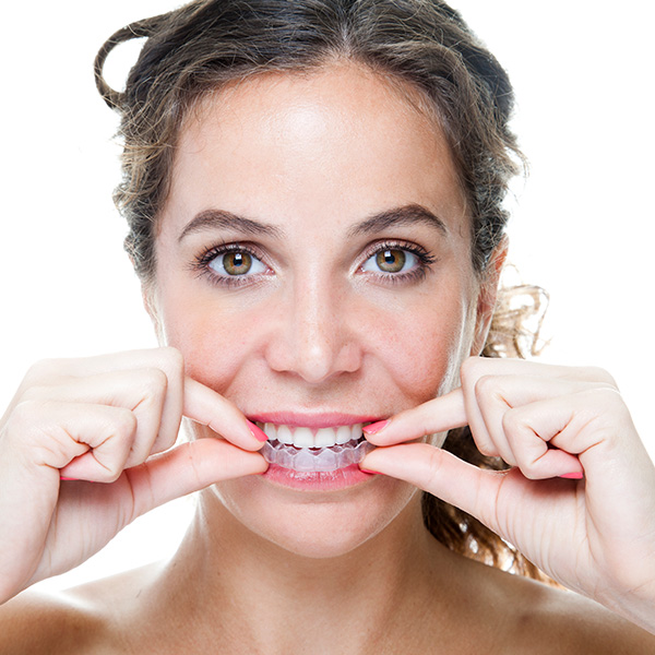 Happy woman smiling putting on her Invisalign treatment